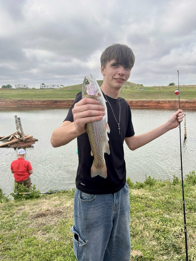 student holding fishing pole and fish 