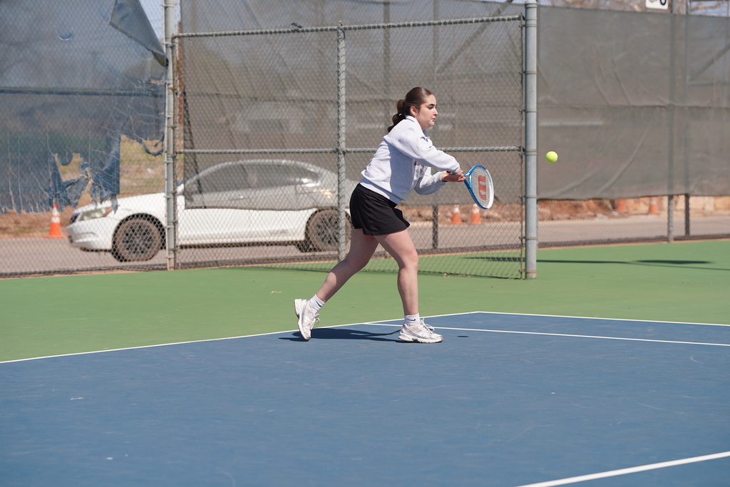 Lady Reds tennis player hitting a backhand shot
