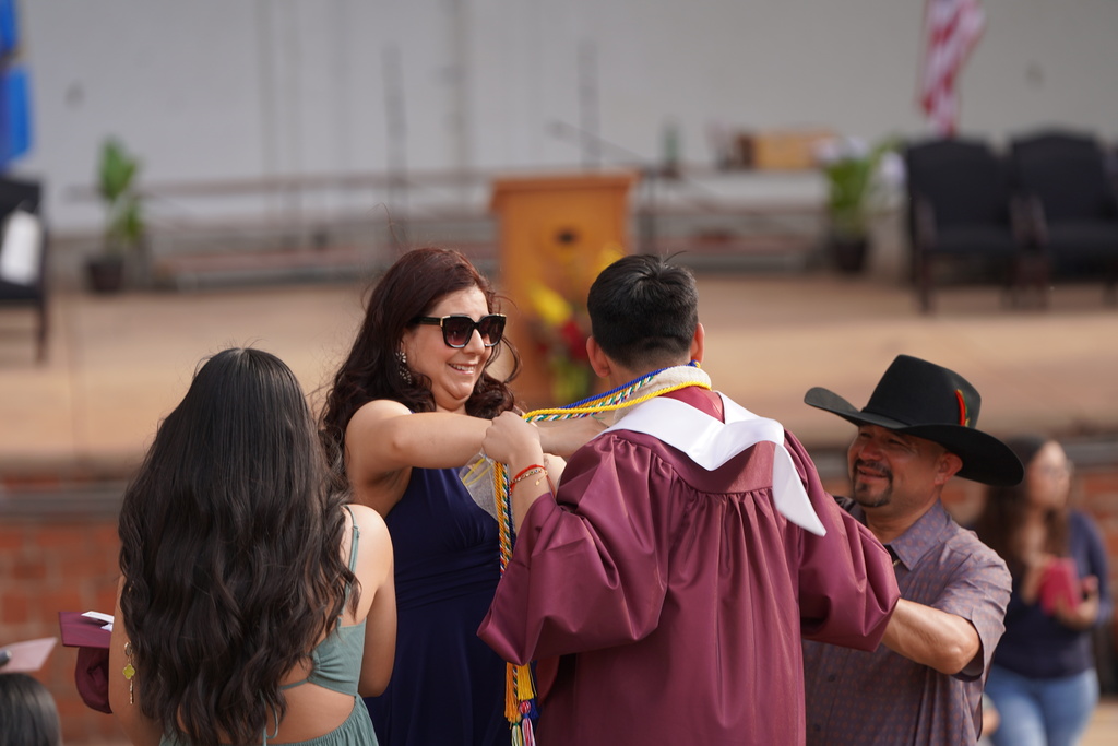 Mom helping senior fix his graduation stoles