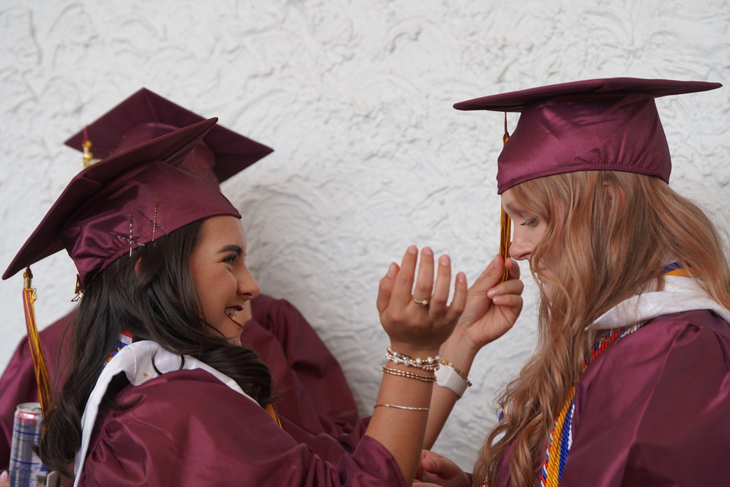 CHS grad laughing and helping friend fix her tassel