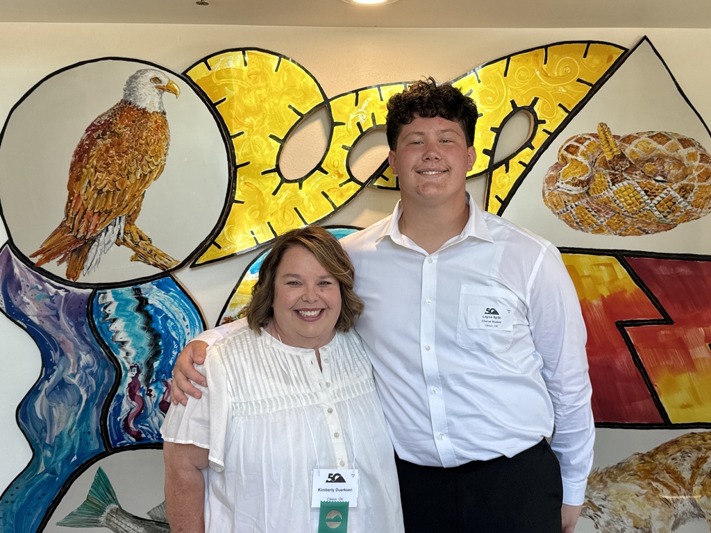 Choir teacher and student standing in front of art display at Quartz Mountain