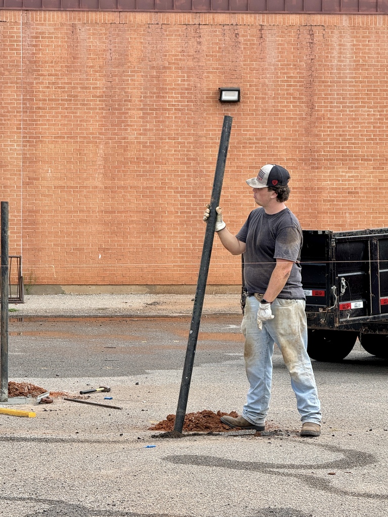 Student worker holding a fence post