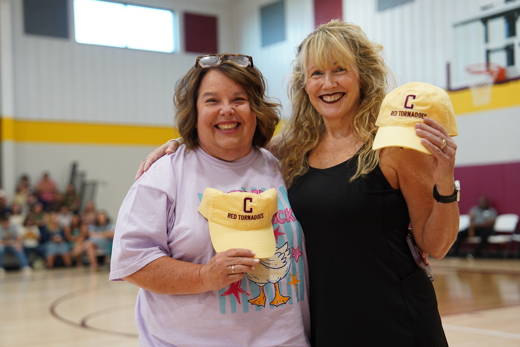 Teachers smiling holding Clinton hats