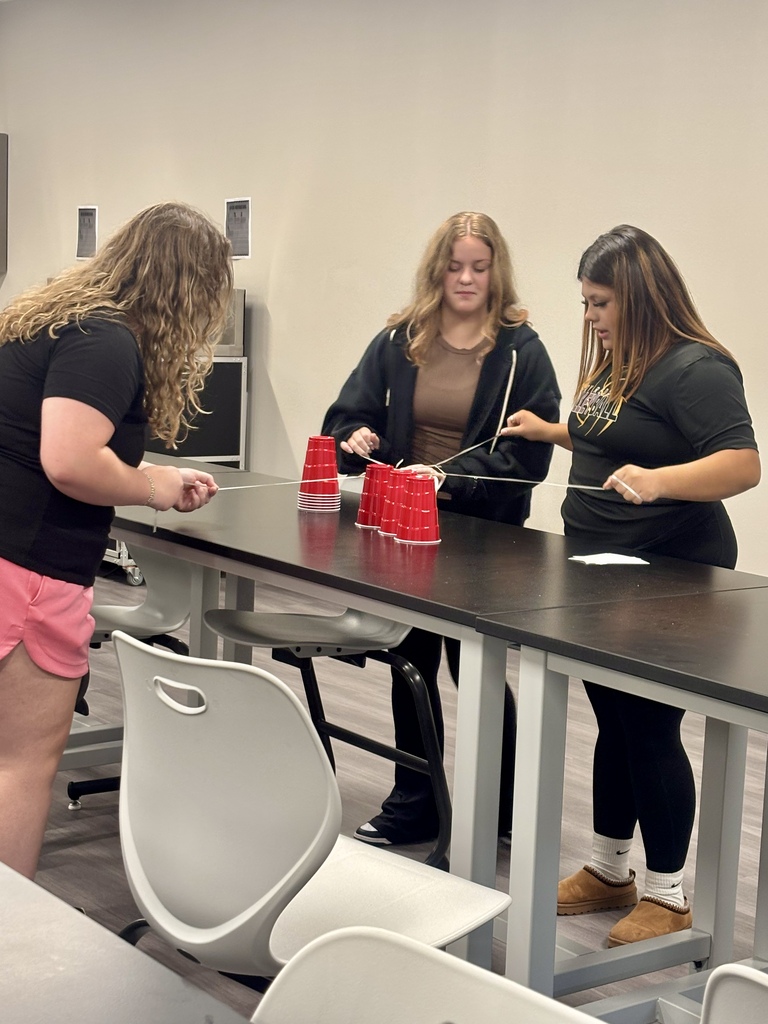 Students using rubber band pulleys on cups
