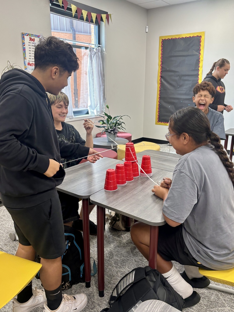Students smiling at table doing a stem activity
