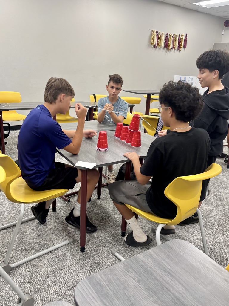 Students at a table doing a cup-stacking activity