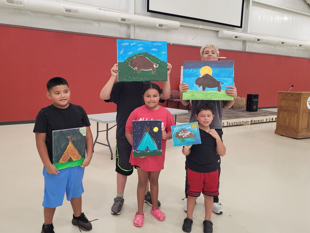 5 students holding paintings of teepees and buffalo