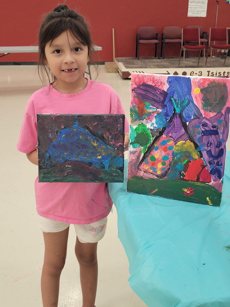 Student standing next to teepee painting