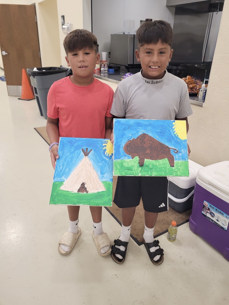 2 students holding paintings of a teepee and buffalo