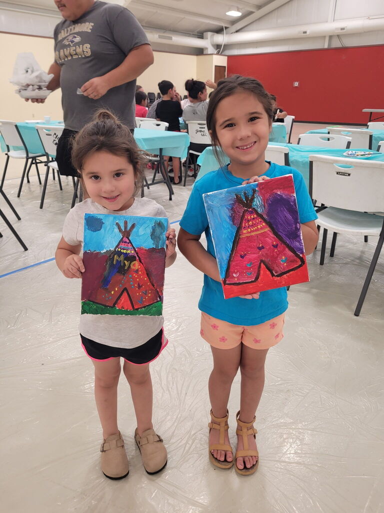 2 students smiling and holding their teepee painting