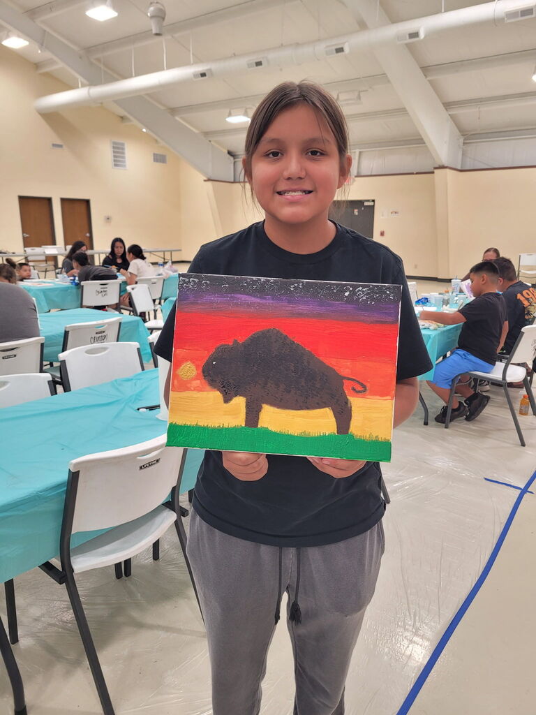 Student standing and holding buffalo painting
