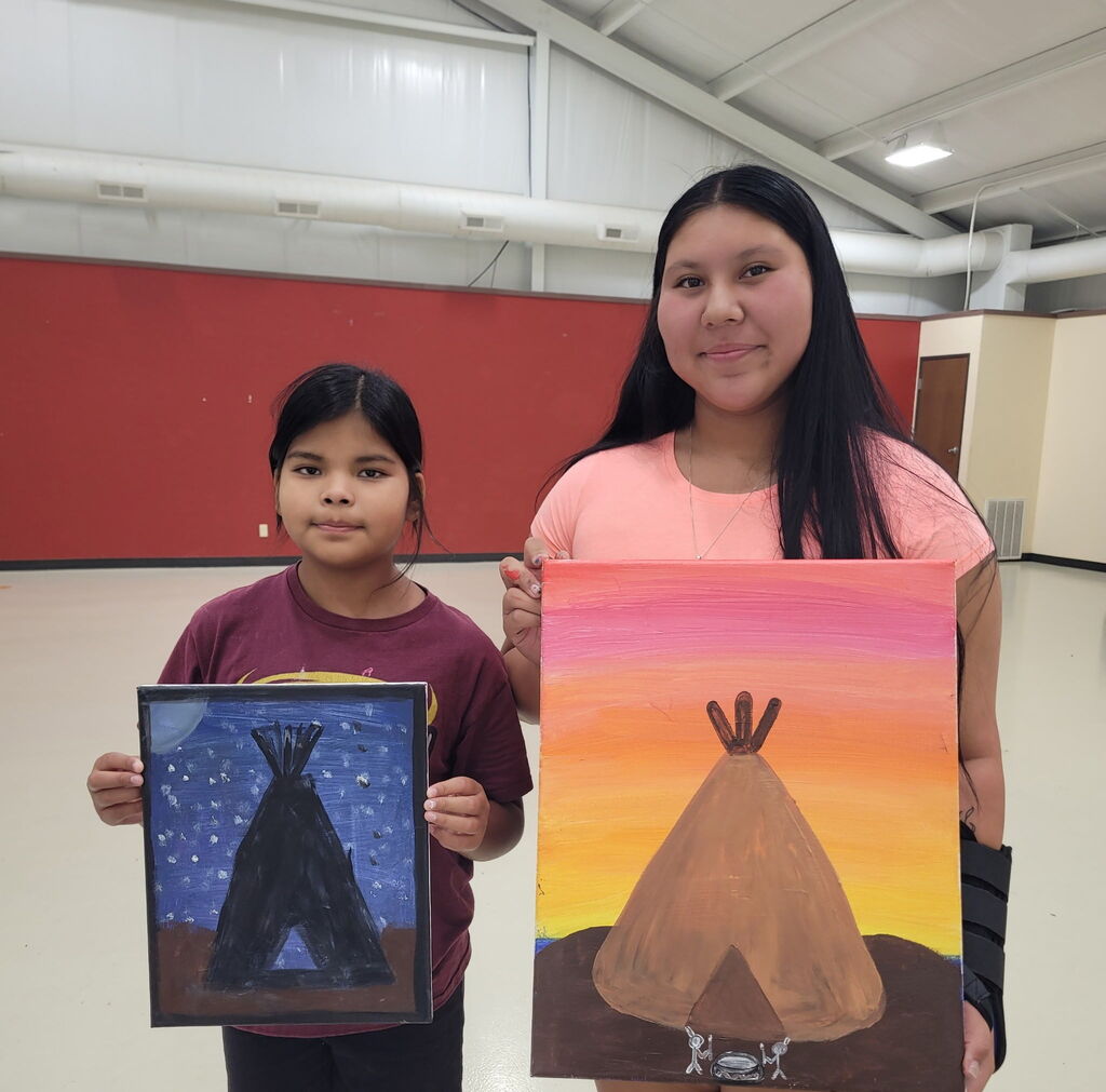 2 students holding paintings of teepees