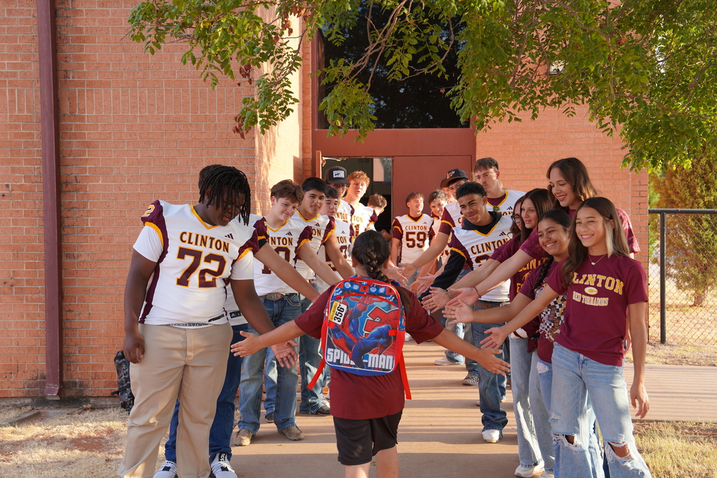 Football players high fiving a student