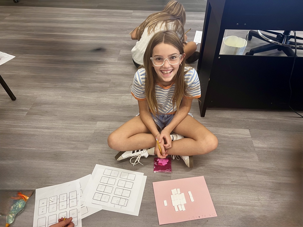 Student smiling at camera while working with dominoes