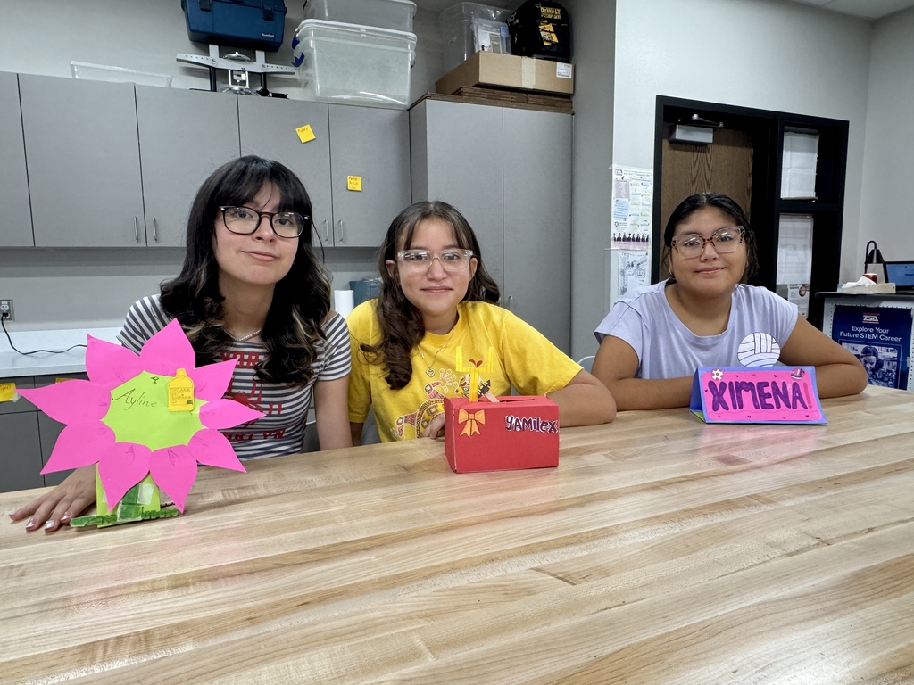 3 students smiling and showing off their name plates