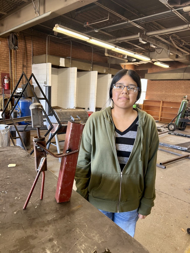 Student standing beside her welding art project