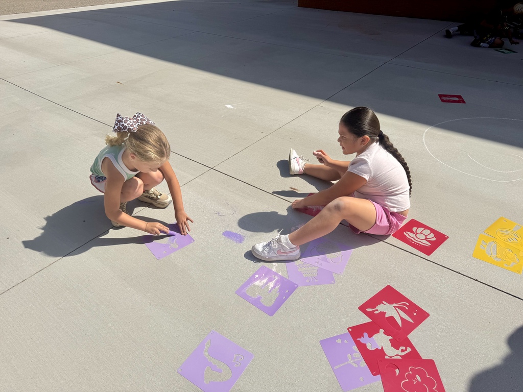 2 Nance students using stencils and chalk on the sidewalk