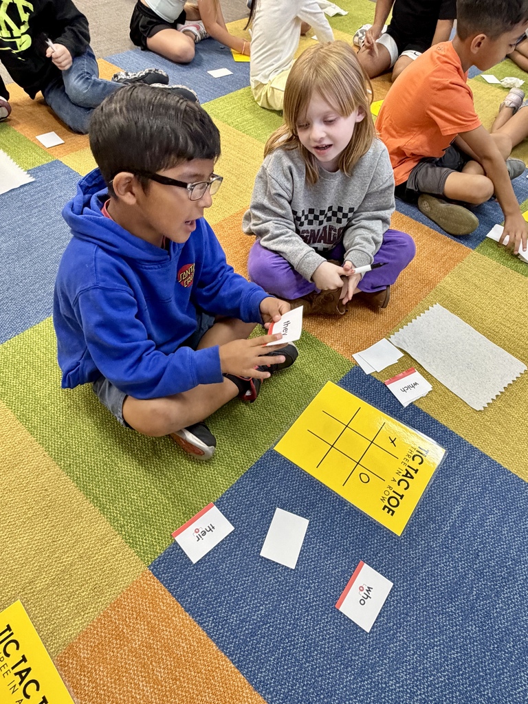 2 students looking at their words and playing red word tic-tac-toe