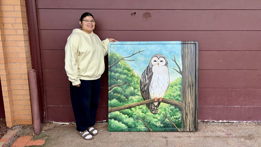 CHS student standing with her owl painting