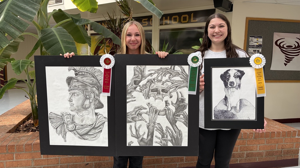 2 students holding their Graphics 2 and Graphics 1 artwork