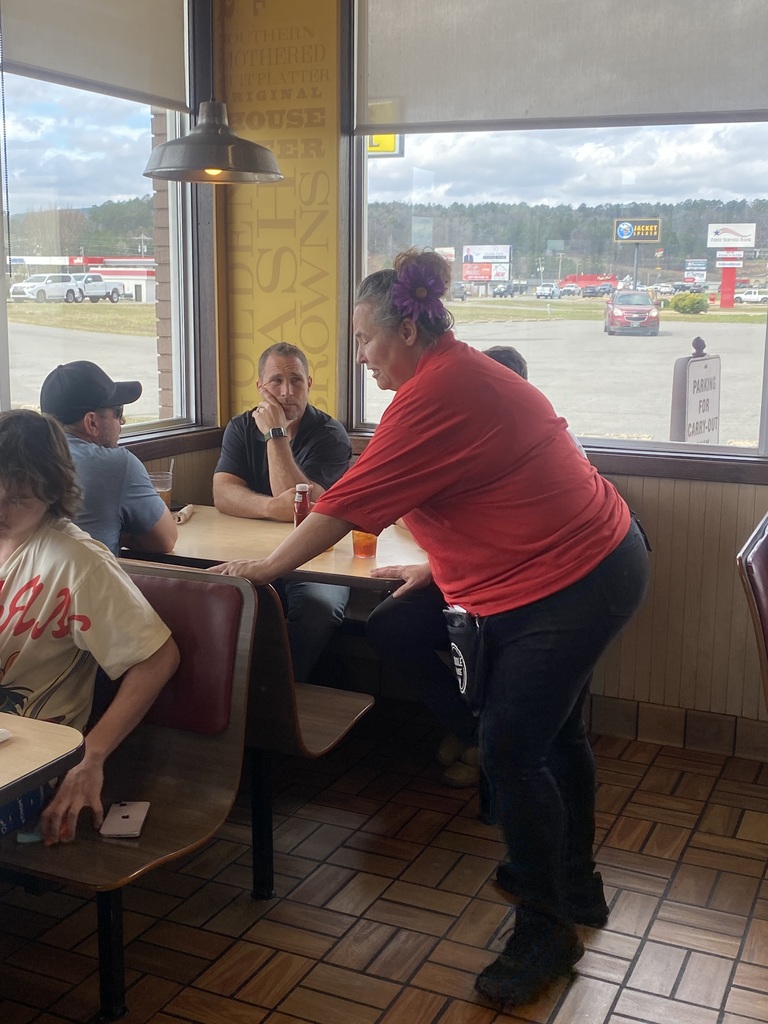 a waitress getting an order for 3 men at a table