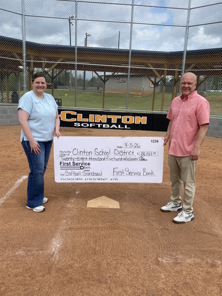 Man and woman holding a large check on a softball field