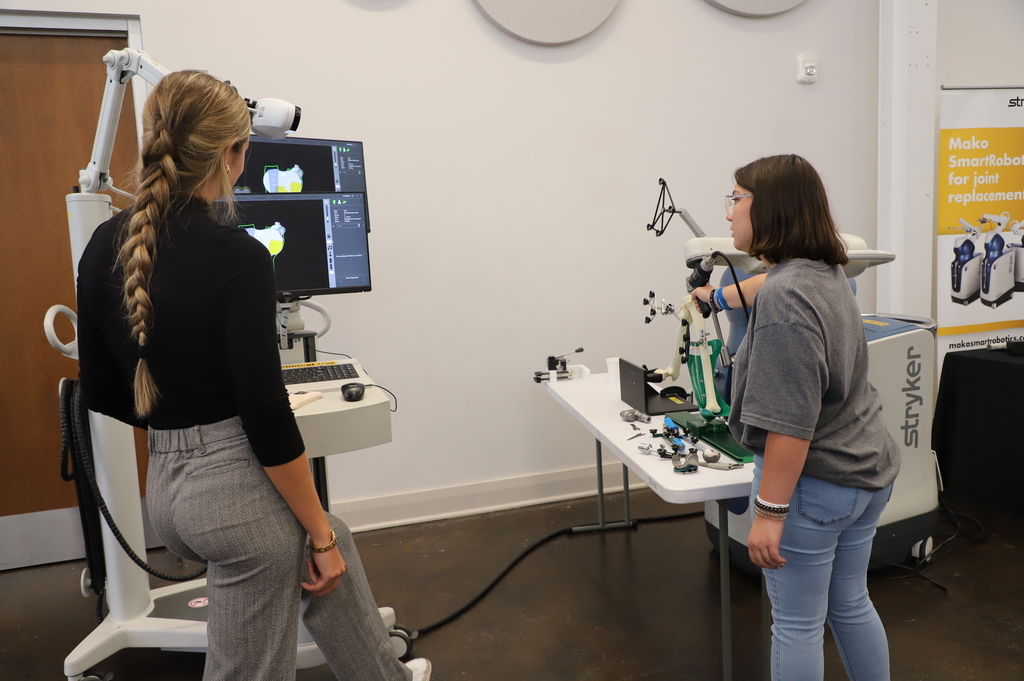 surgical robot technician instructs student on robot manipulation