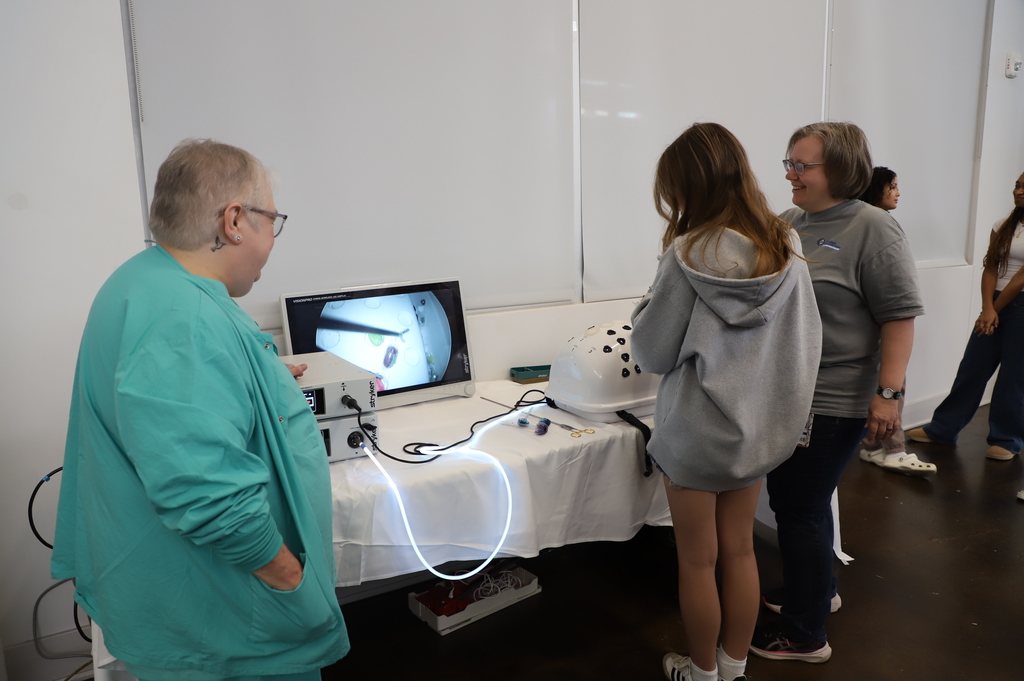 teacher and surgical robot technician work with student on surgical robot use