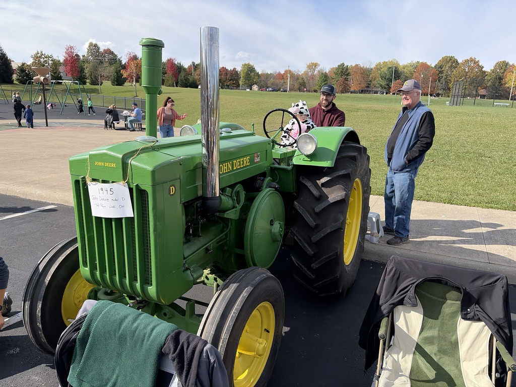 Child in cow costume sitting on John Deere tractor