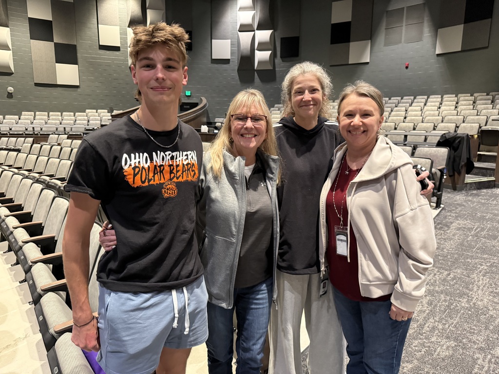 Student in Ohio Northern University shirt standing with some of his teachers