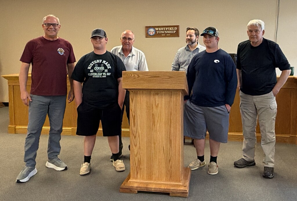 Greg Valent, students and trustees around new podium