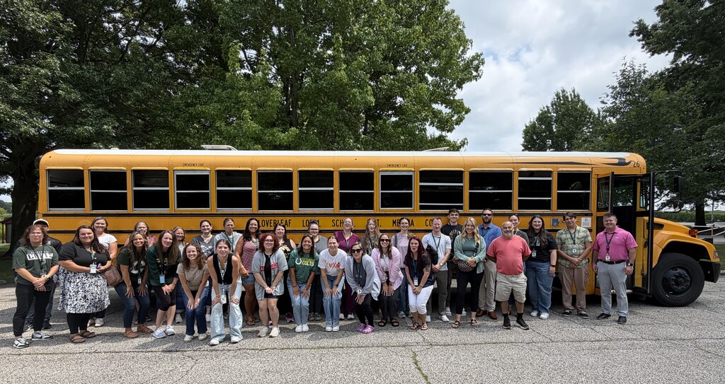 New Cloverleaf staff members posing beside a school bus