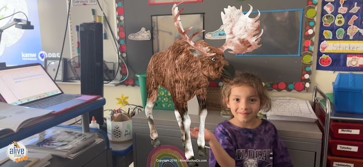 A young student holds up an image of a moose.