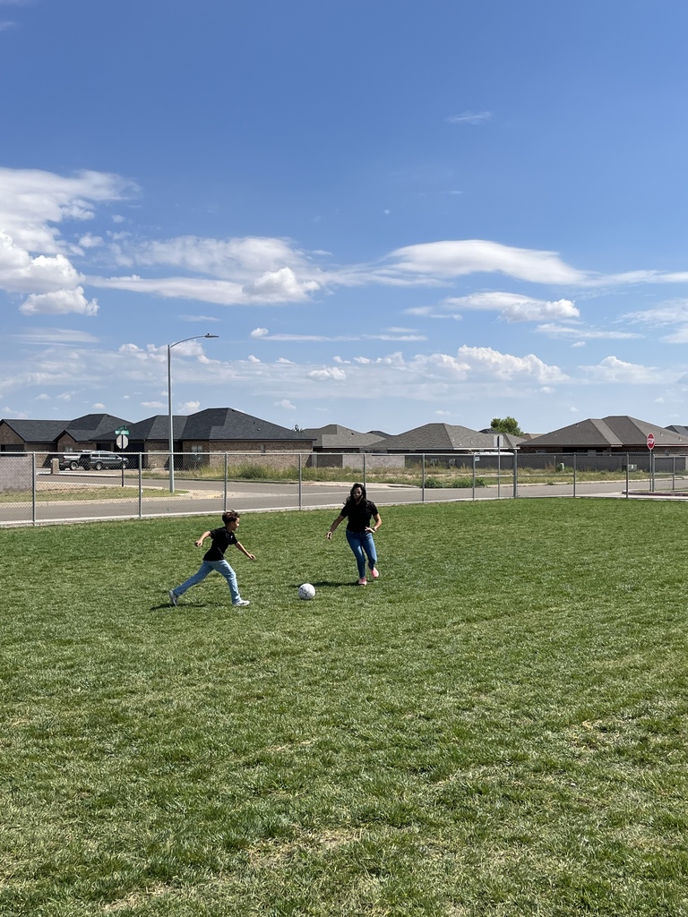 Teacher and student playing soccer in the field,].
