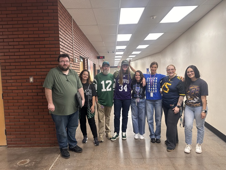 Faculty stands in hall wearing jerseys