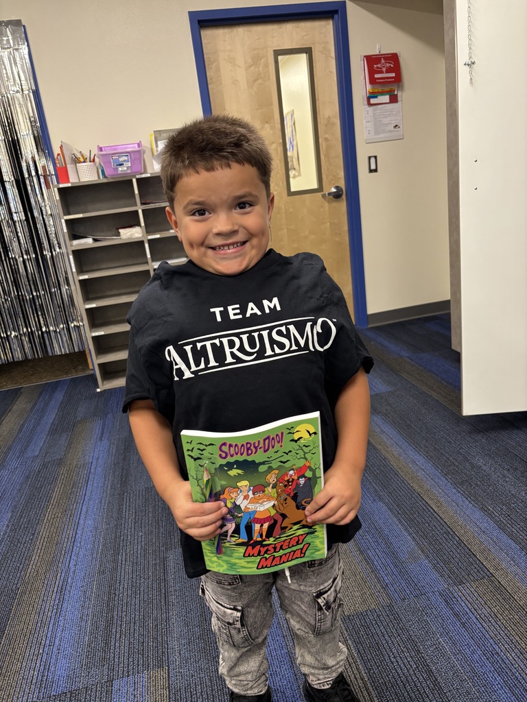 Smiling kindergarten student, holding a Scooby Doo book.