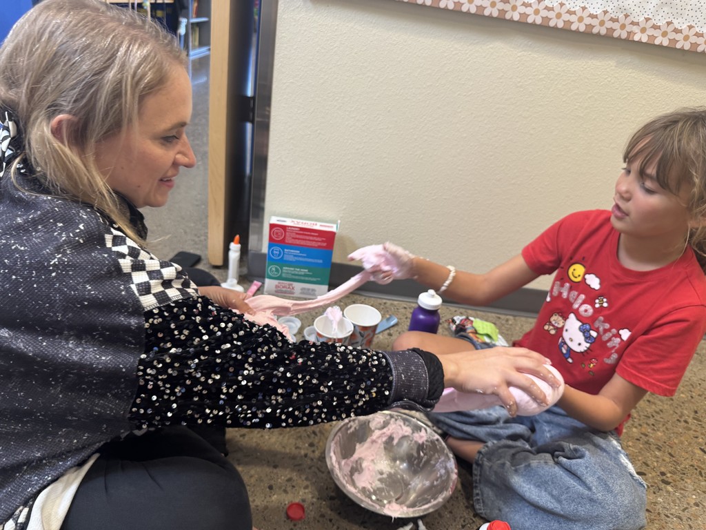 Teacher and student sitting on the floor. Playing with fluffy slime.