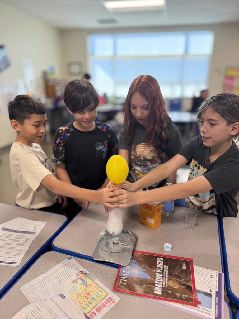 4 students holding onto a water bottle with a deflated balloon on top