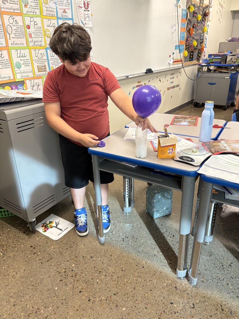 One student standing, looking at his science project