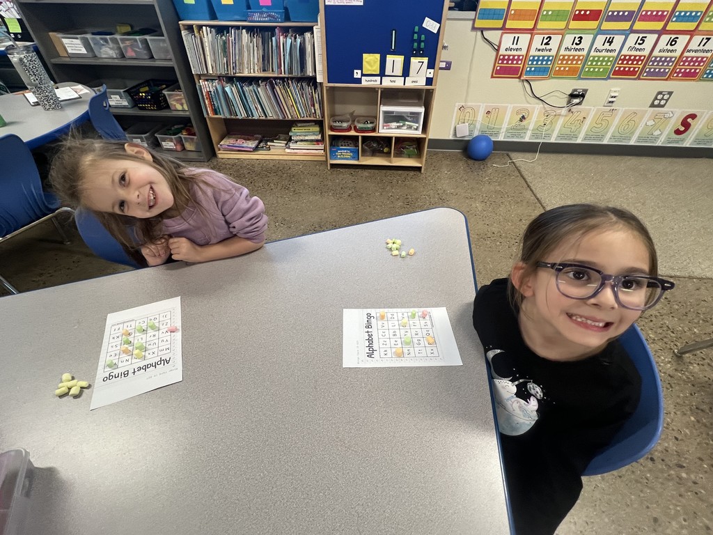 Two girl students smiling at the teacher while working