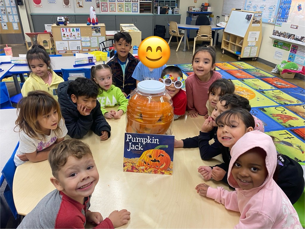 Children sitting around the table and the pumpkin sitting in the bucket with the book of the pumpkin jack. 