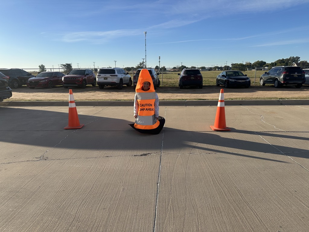 A person dressed as a traffic cone sitting next to two other traffic cones. 