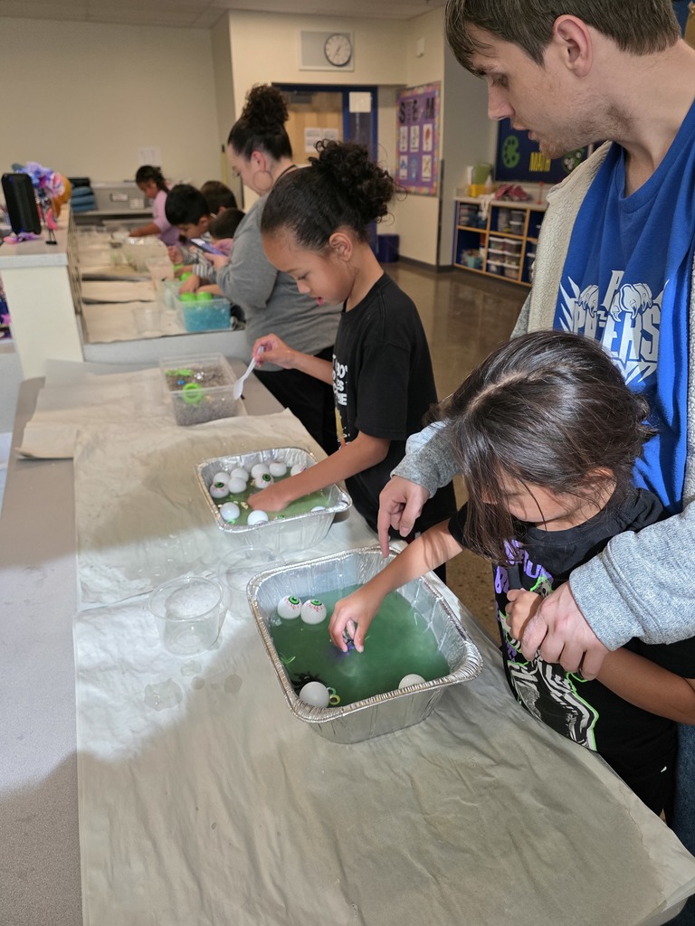 students playing with fake eye balls in slime. One is being assisted by a staff member