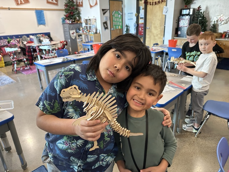 a pair students holding puzzle dinosaurs