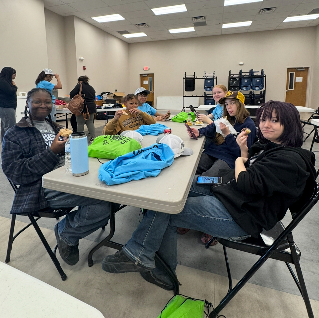 A group of people eating at a table inside a room. One person holds a water bottle.