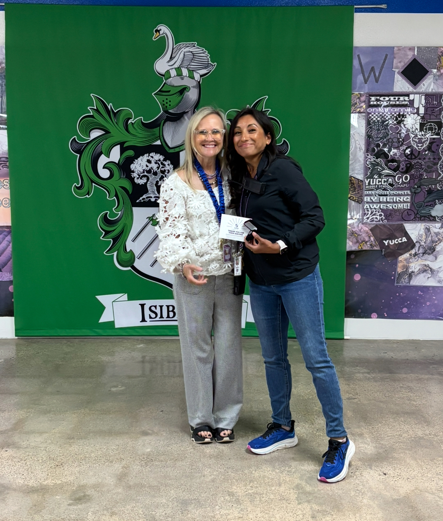 Two women stand in front of a green backdrop with a crest and text reading "SIB." One holds a certificate, and the other wears a badge.