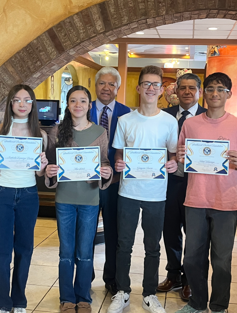Six individuals stand in a row, holding certificates. They are under an archway. A tiled floor and a decorative wall are behind them.