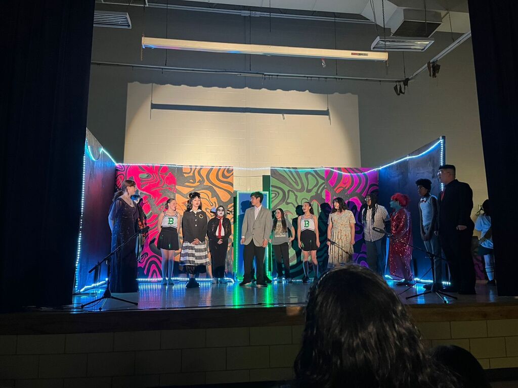 A group of people stands on a stage with a backdrop of colorful, abstract art.