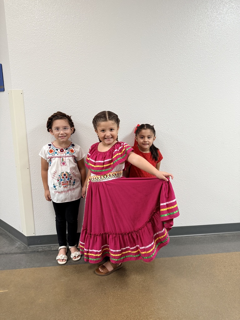 Three children in a room, one in a pink skirt, another in a white shirt, and one in red.