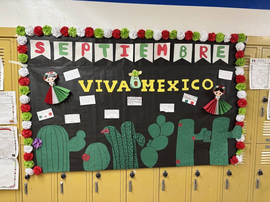 A colorful classroom bulletin board with September text, "Viva Mexico," and paper cutouts of cacti and traditional figures. Lockers are in the background.